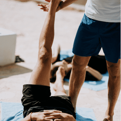 A fitness instructor helping a fitness member stretch their leg A fitness instructor helping a fitness member stretch their leg