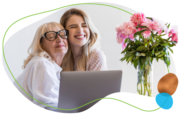 happy grandmother hugging granddaughter on a laptop