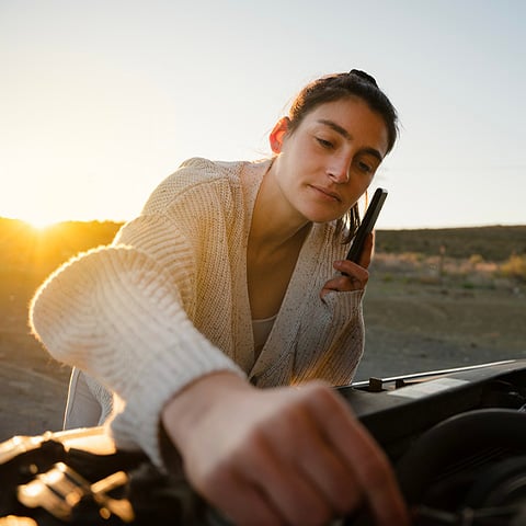 Woman fixing broken down car