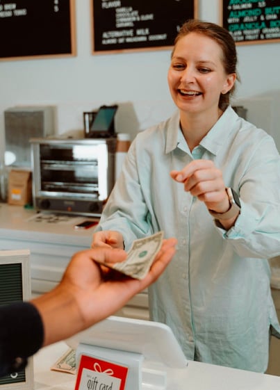 Woman in white button up handing cash to customer