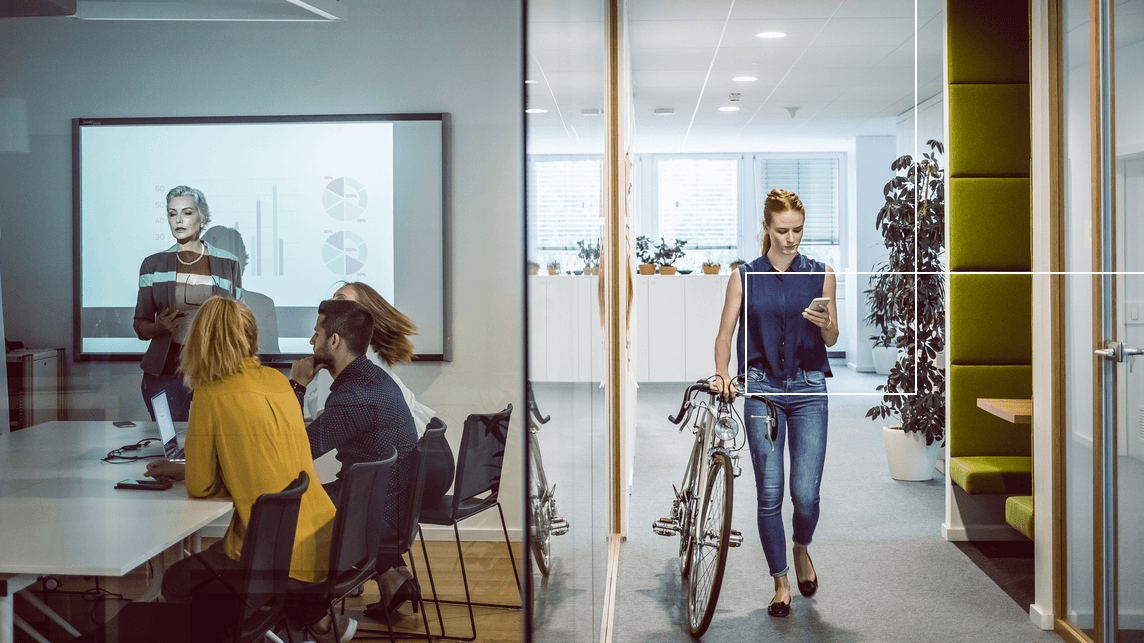 Woman walking into office passing by meeting room on her phone