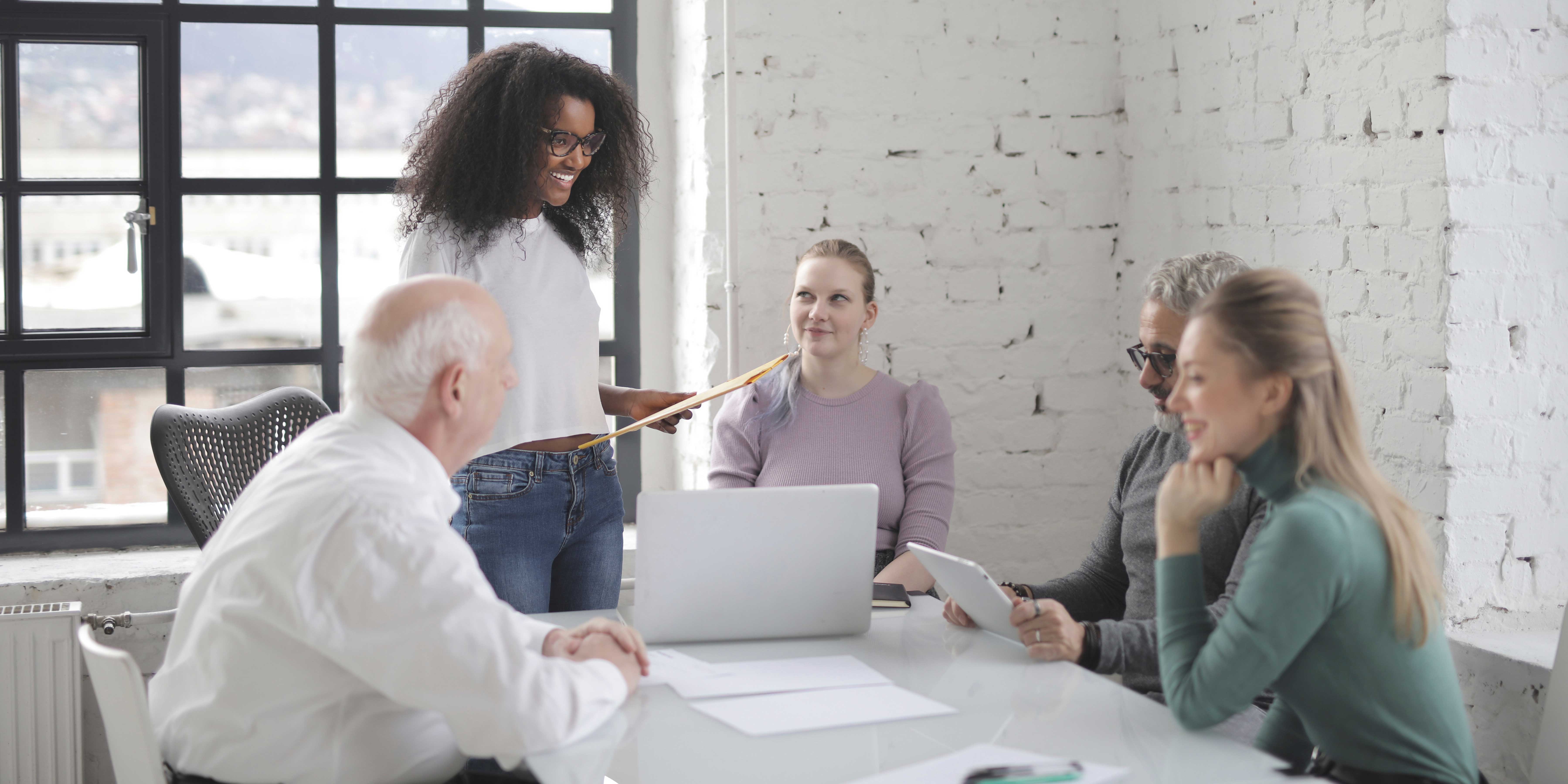 Office workers gathered at meeting room table discussing