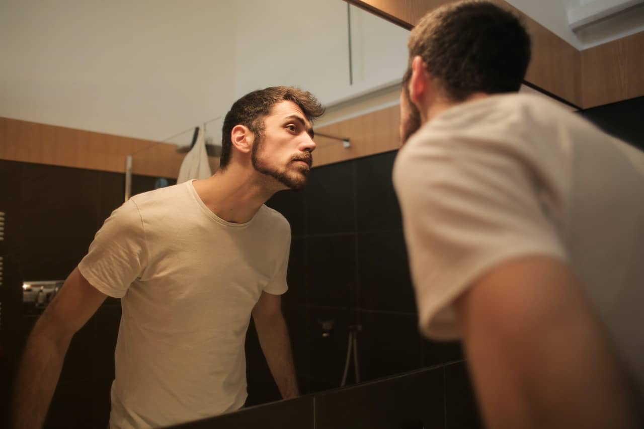 Man looking at skin in mirror