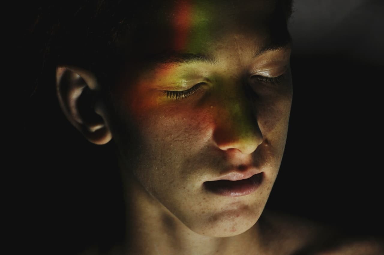 Man with rainbow light across face