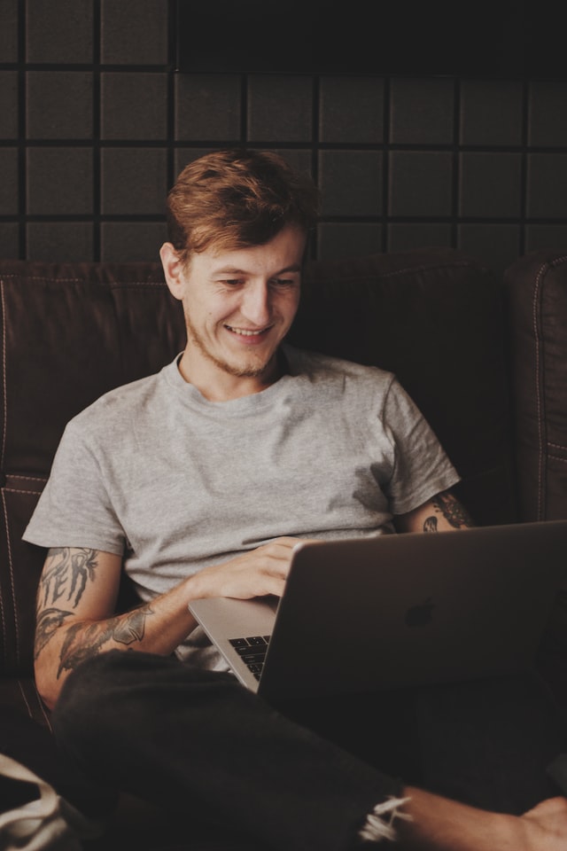 Happy man on sofa with laptop