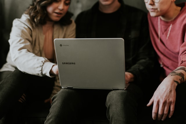 Three people looking at a laptop - small