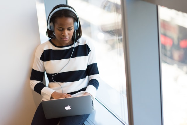 Woman with headphones and Macbook