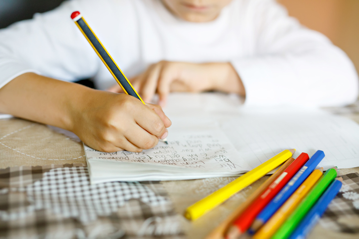 child with autism practicing writing words with different colored pencils