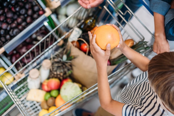 little child with autism helping parent during shopping in grocery shop