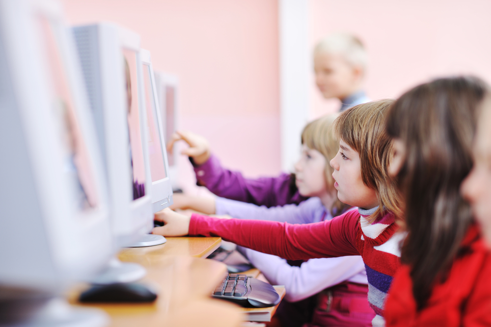 it education with children group in school at computer science class learning leassons and practice typing