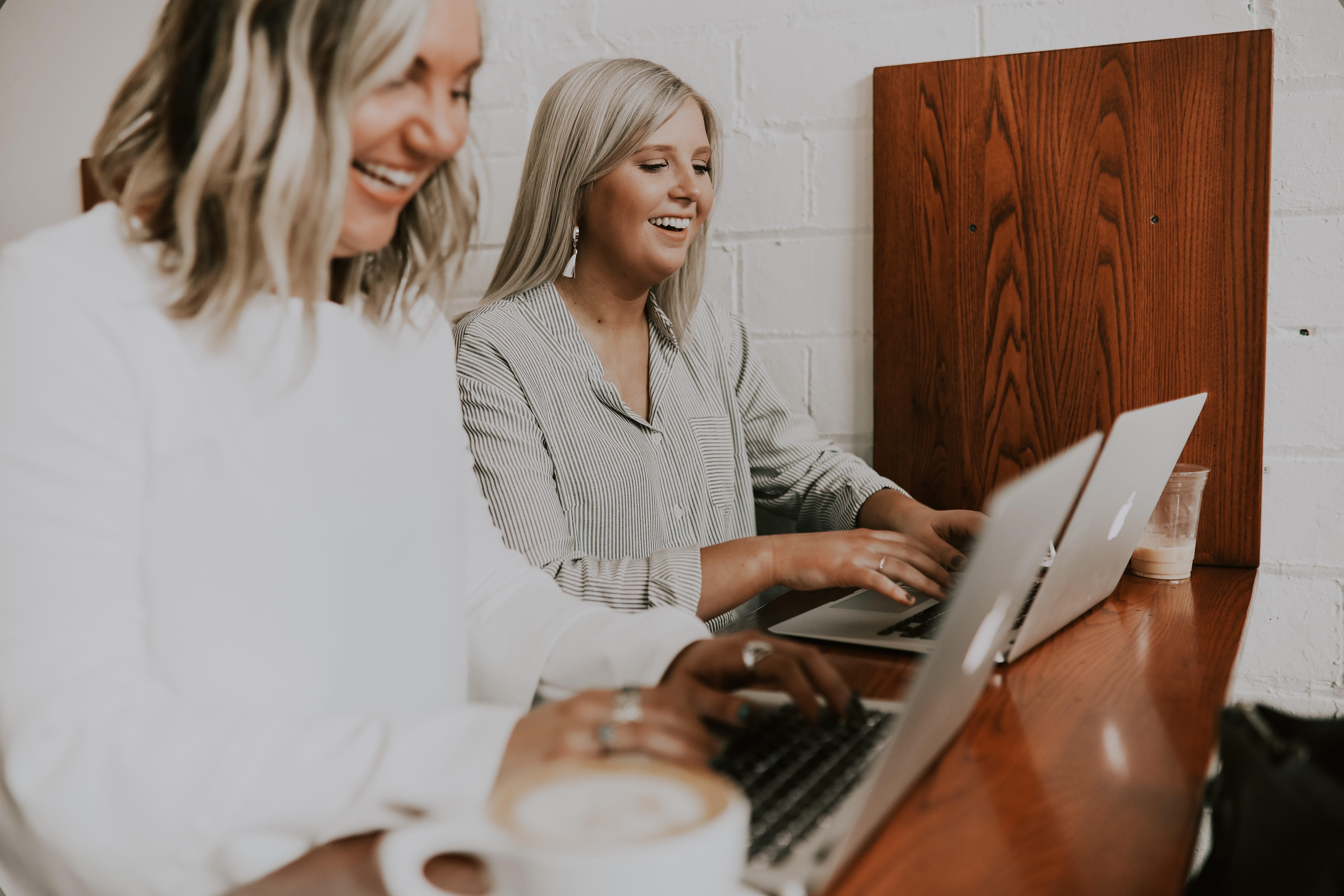 Happy women working on Macs drinking lattes