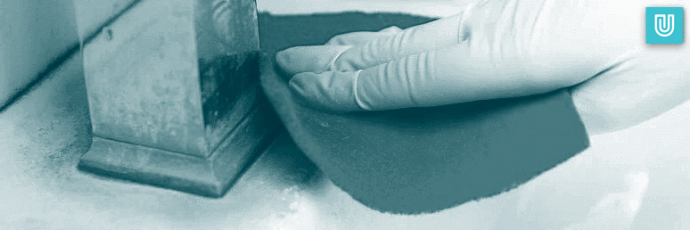 Choosing the right nitrile gloves for cleaning is very important. Here a cleaner is using nitrile cloves that are abrasion and chemical resistant as she uses a scouring pad to clean a work surface.