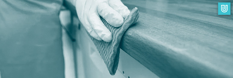 Disposable nitrile gloves being worn by a professional cleaner who is wiping down a worktop.