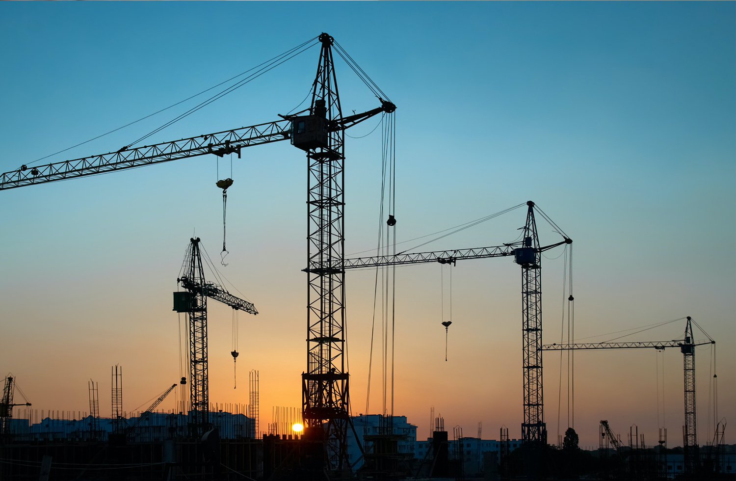 tower cranes on sunset city skyline