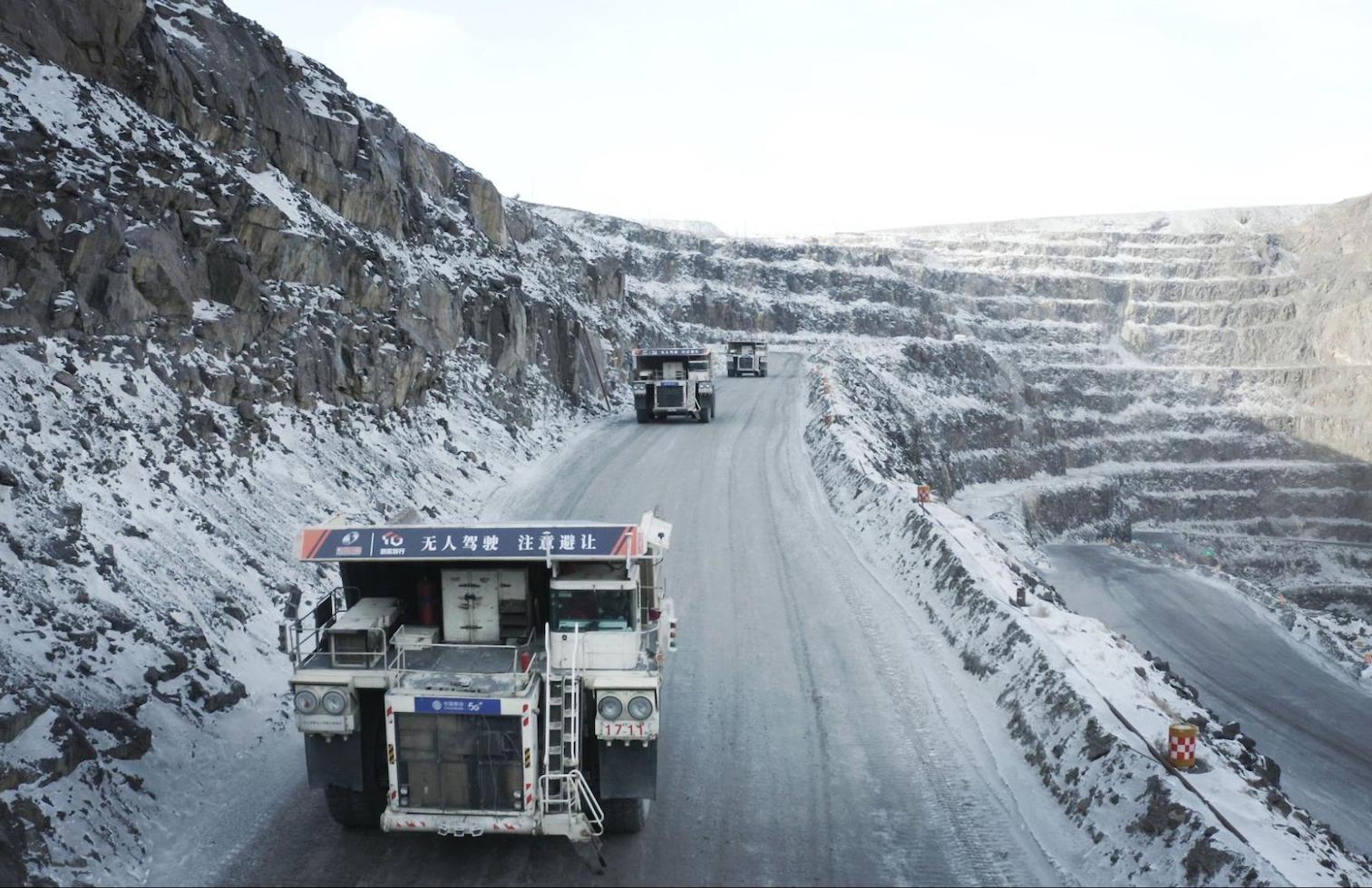 Mining trucks driving on road in open pit mine