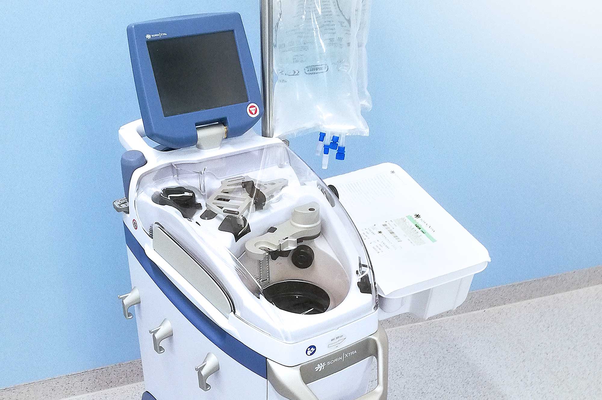 Medizinisches Gerät mit Monitor und Flüssigkeitsbeuteln in einem Klinikraum