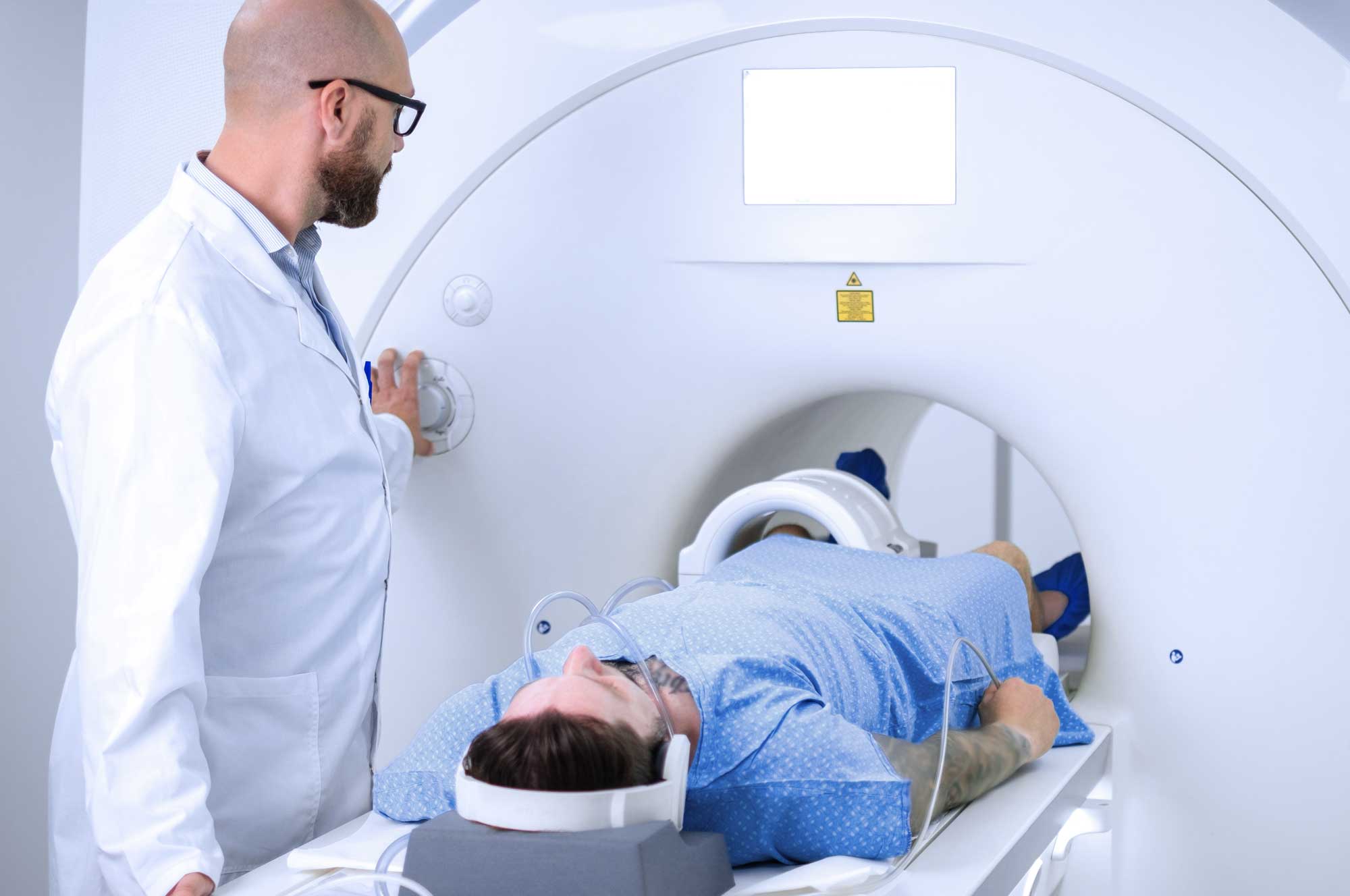 Ein Patient liegt in einem MRT-Gerät, während ein Arzt die Untersuchung bedient.