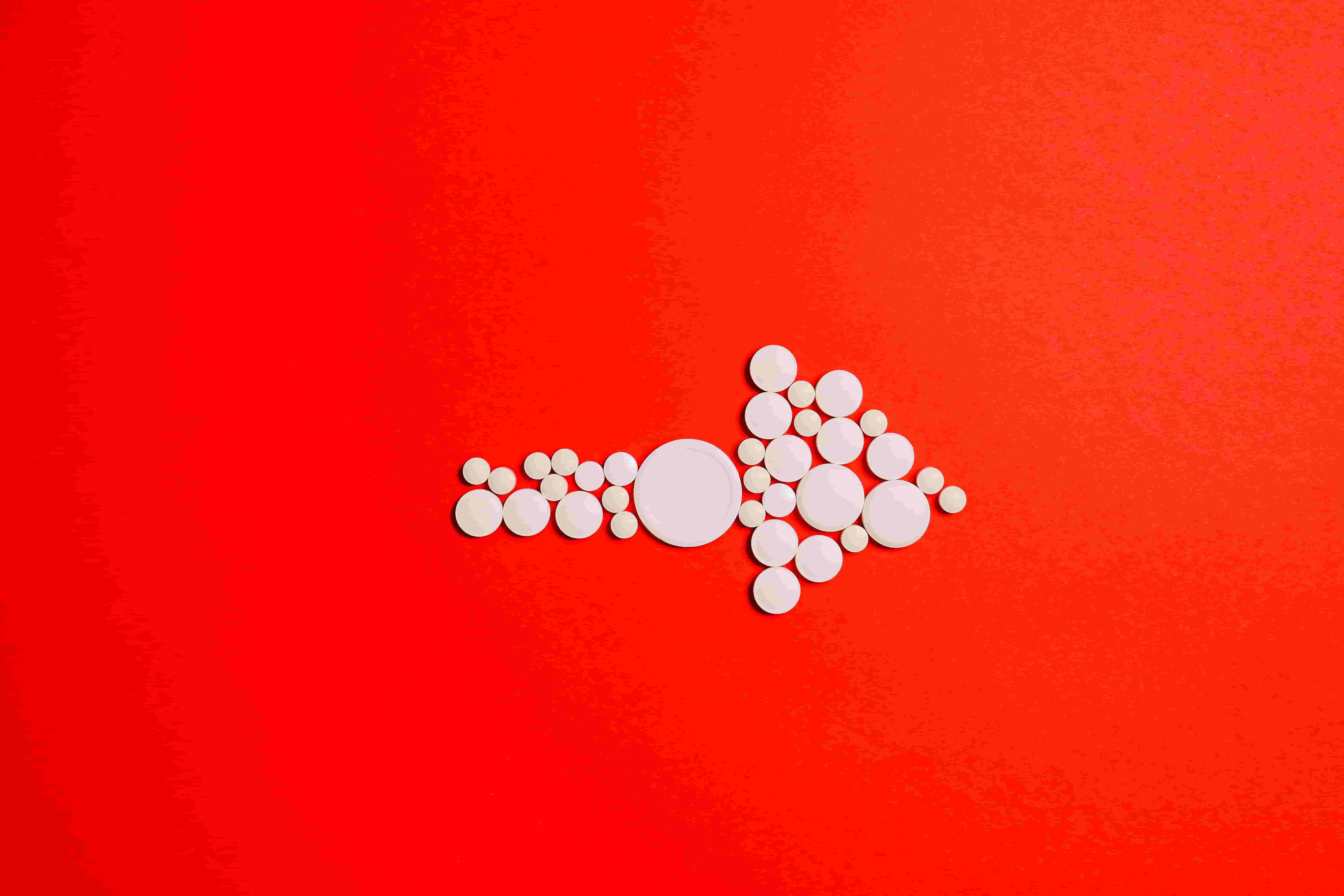 white pills on a red background pointing to the right