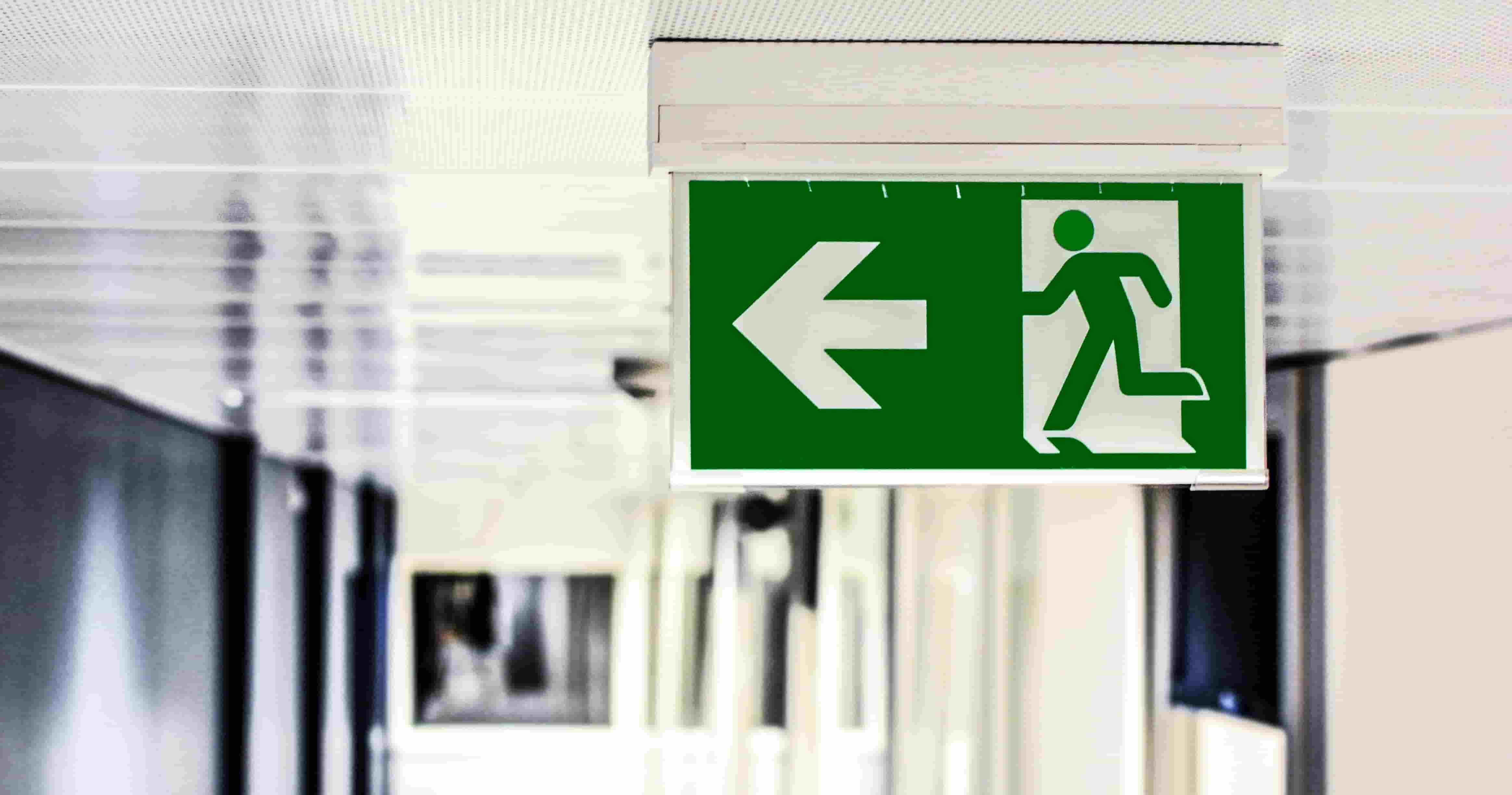 a green sign in a hospital with an arrow to the left