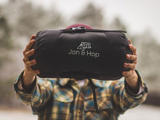 A man holding up a Jon & Hop sleeping bag