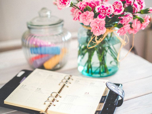 A daily planner with a vase and glass jar in the background