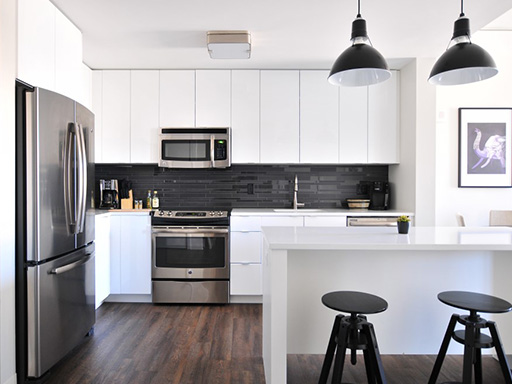 Modern kitchen with white cabinets, stainless steel fridge, and black accents