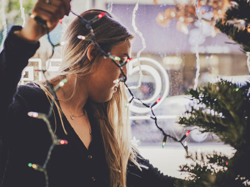 Woman putting string lights on a Christmas tree